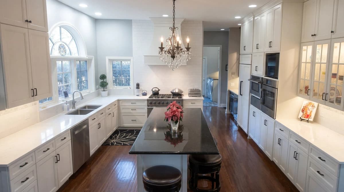Spacious kitchen with white cabinets and marble counters.