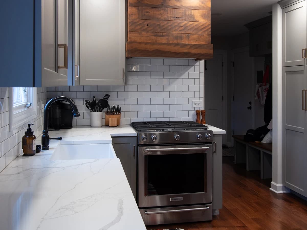 Modern kitchen with a gray and white color scheme, white cabinets, black and white countertops,