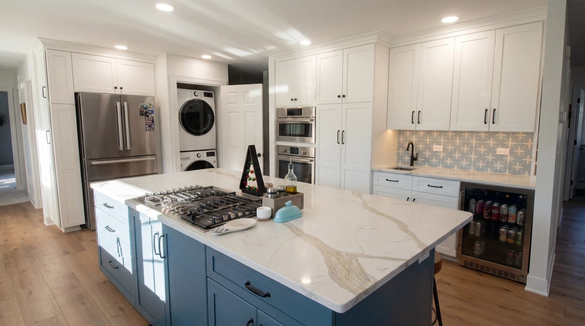Modern kitchen with white cabinets, marble countertops, stainless steel appliances, and a black